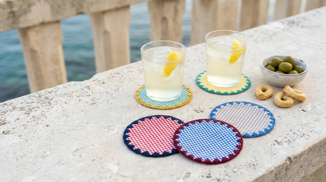 Round gingham coasters with a zigzag edge under two glasses on a stone ledge